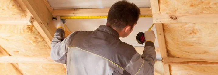 Person misst Dachbalken mit Zollstock